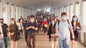 Bangkok, Thailand - Apr 7, 2020: Crowded Asian people wear face mask walking in pedestrian walkway. Coronavirus disease Covid-19 pandemic outbreak effect on human, city life, or air pollution concept